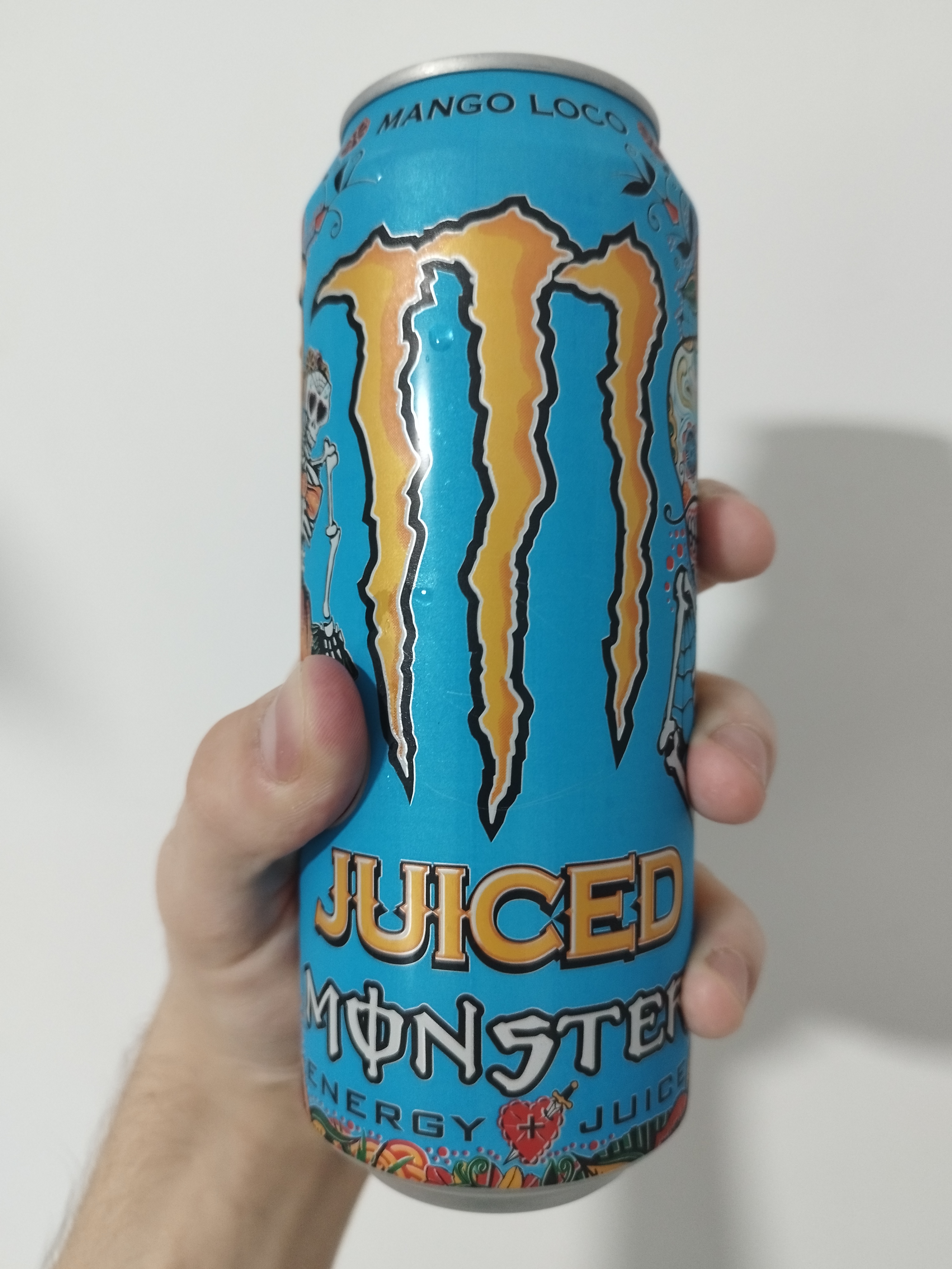 a light-blue coloured juiced monster mango loco. on the can are day-of-the-dead-adjacent illustrations depicting decorated skeletons.