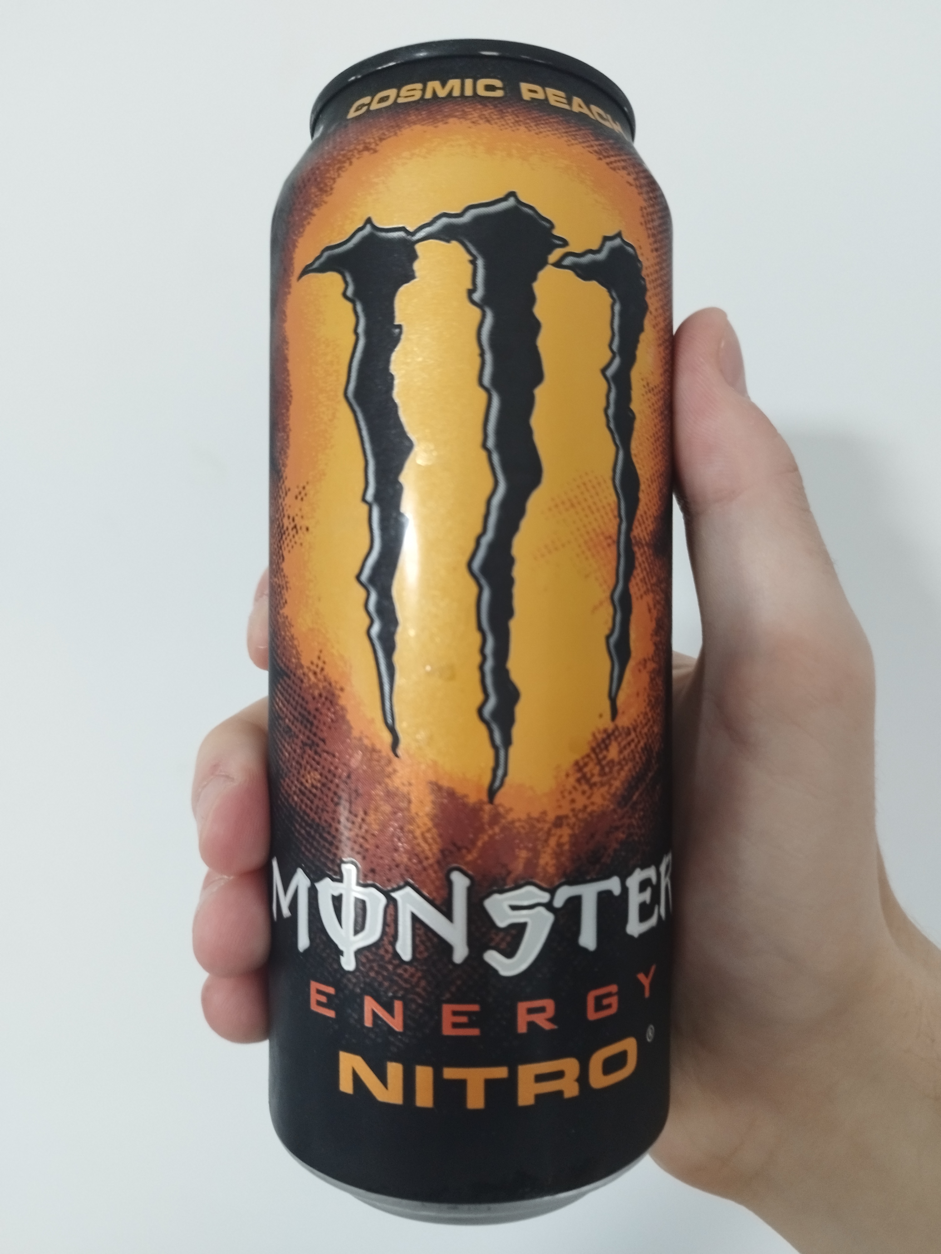 a black can of nitro cosmic peach. behind the logo, there's an orange halftone pattern.