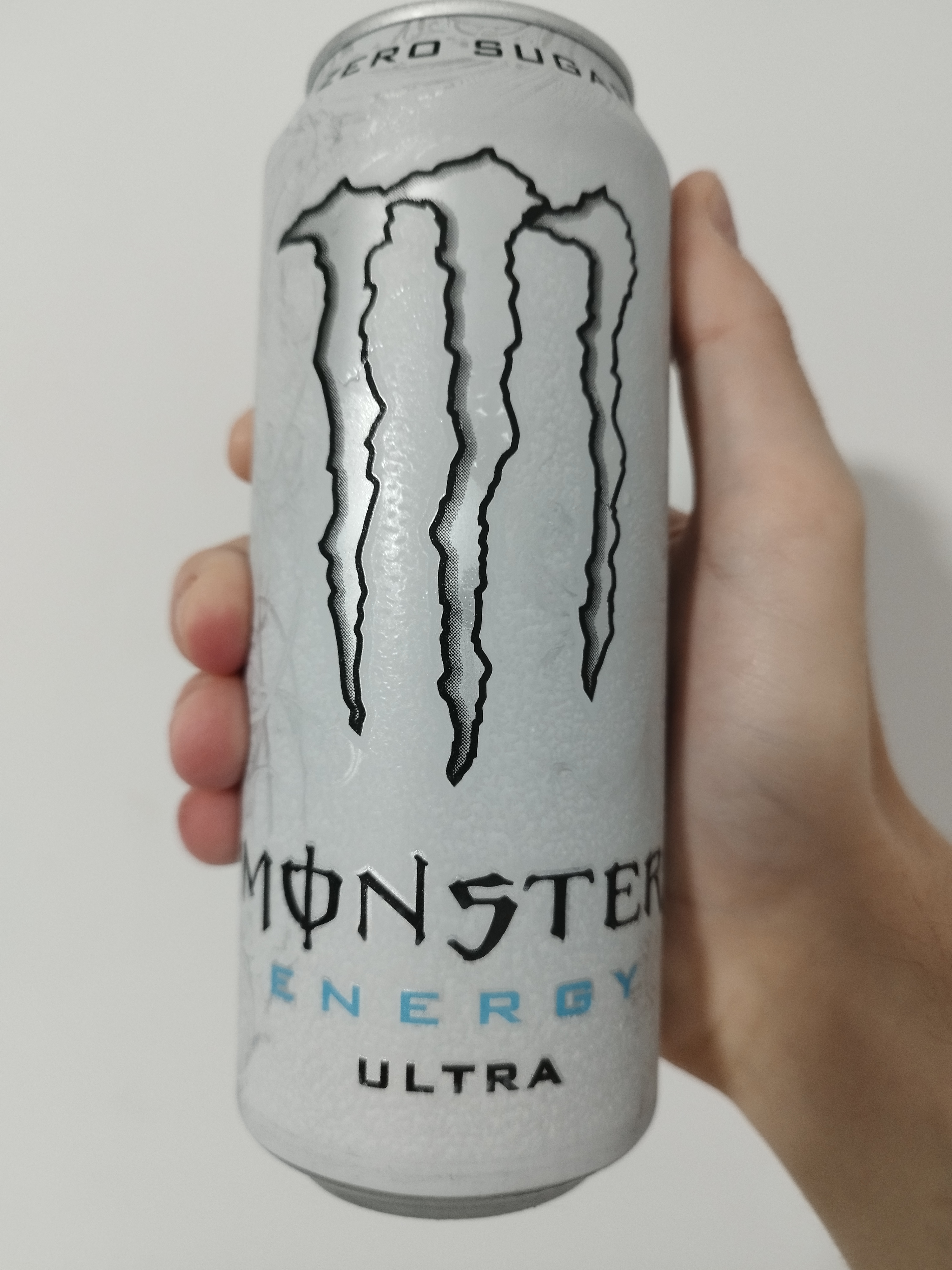 a white can of white monster with silver swirling plant-like patterns behind the main logo.